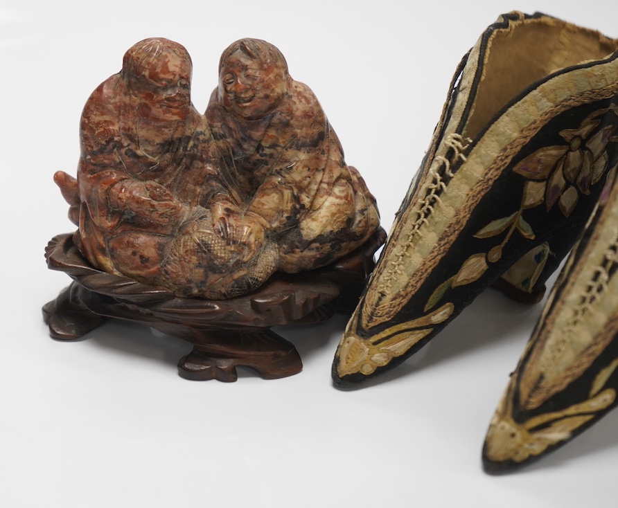 A pair of Chinese black silk embroidered ‘foot bound’ ladies shoes and a soapstone group of HeHe Erxian on carved stand, soapstone carving on stand 8cm high (3). Condition - fair to good